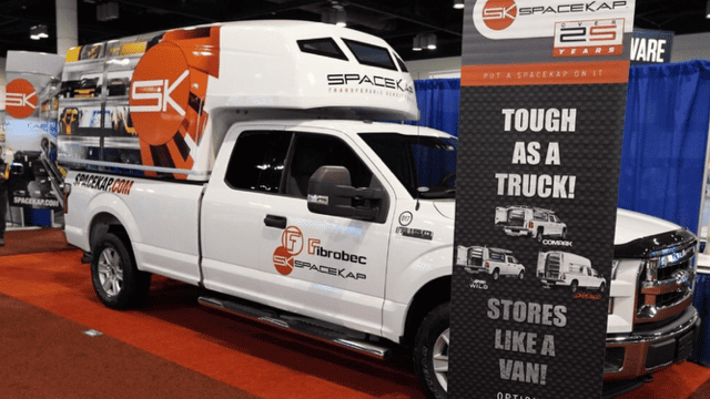 Camion blanc équipé d'une benne SpaceKap avec signalisation publicitaire lors d'un salon professionnel