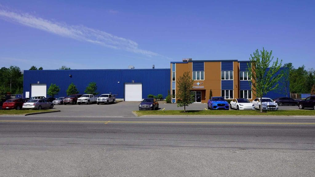 Façade d'un bâtiment industriel bleu et marron avec plusieurs voitures garées devant sous un ciel bleu clair