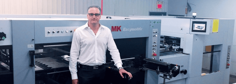 Homme debout devant une machine industrielle de découpe MK Easymatrix dans un atelier